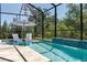 A refreshing screened pool with lounge chairs offering a serene retreat with a view of lush greenery at 5621 Badini Way, Palmetto, FL 34221