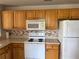 Kitchen featuring white appliances, wooden cabinets, and backsplash at 5681 Bentgrass Dr # 13-201, Sarasota, FL 34235