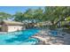 Community pool and spa area with lounge chairs, umbrellas, and lush green trees surrounding the area at 5688 Pipers Waite # 50, Sarasota, FL 34235