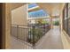 Hallway with dark metal railing and neutral walls leads to an outdoor scene with a view of trees at 6460 Mourning Dove Dr # 204, Bradenton, FL 34210