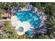 Aerial view of a community pool surrounded by lush landscaping, lounge chairs, and a hot tub at 6460 Mourning Dove Dr # 204, Bradenton, FL 34210