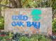 Community sign for Wild Oak Bay framed by beautiful greenery and colorful flowers at 6460 Mourning Dove Dr # 204, Bradenton, FL 34210