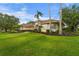 Beautifully landscaped home with a lush green lawn, mature trees, and a meticulously maintained exterior at 6637 Taeda Dr, Sarasota, FL 34241