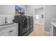 Well-equipped laundry room with front load washer and dryer, sink, white cabinets, and artwork at 6637 Taeda Dr, Sarasota, FL 34241