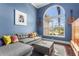 Stylish living room with blue walls, a comfortable gray sofa, and large arched window with natural light at 6637 Taeda Dr, Sarasota, FL 34241