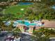 Aerial view showcases the community pool with lounge chairs, lush landscaping and golf course in the background at 7015 River Hammock Dr # 204, Bradenton, FL 34212
