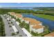 Aerial view of condos with red tile roofs, parking, landscaping, and a body of water behind them at 7015 River Hammock Dr # 204, Bradenton, FL 34212