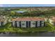 An exterior shot showcases a lakefront condo building with balconies and lush landscaping at 7015 River Hammock Dr # 204, Bradenton, FL 34212