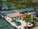 Aerial view of community tennis courts, lush landscaping, and a cozy clubhouse at 7015 River Hammock Dr # 204, Bradenton, FL 34212