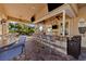 Inviting covered outdoor bar area with granite countertops, seating, televisions, and ceiling fans at 8004 River Preserve Dr, Bradenton, FL 34212