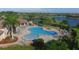 Aerial view of the clover-shaped pool, lounge chairs, and verdant tropical landscaping by the community clubhouse at 8004 River Preserve Dr, Bradenton, FL 34212