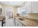 Galley kitchen featuring granite countertops, white cabinets, and stainless steel sink at 8798 Herbison Ave, North Port, FL 34287