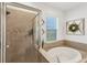 Bathroom featuring a glass-enclosed shower, soaking tub, window and decorative wall art at 11037 77Th E St, Parrish, FL 34219