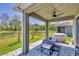 Covered patio with ceiling fan, outdoor seating and cooking space overlooks fenced yard and pond at 11037 77Th E St, Parrish, FL 34219
