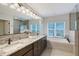Bright bathroom featuring double granite vanity, soaking tub under window, and glass shower at 1110 93Rd Nw St, Bradenton, FL 34209