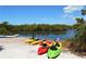 Several colorful kayaks are resting on a white sandy beach, ready for a day of paddling on the tranquil waterway at 1110 93Rd Nw St, Bradenton, FL 34209