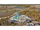 Aerial view of a resort-style pool with waterslides, cabanas, and lounge chairs surrounded by lakes and landscaping at 11221 Gallatin Trl, Parrish, FL 34219