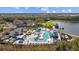 Aerial view of a resort-style pool with waterslides, cabanas, and lounge chairs surrounded by landscaping at 11221 Gallatin Trl, Parrish, FL 34219