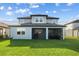 Back exterior view of a two-story home, showing the patio, grassy yard, and clean architectural lines at 11221 Gallatin Trl, Parrish, FL 34219