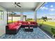 Cozy screened patio with comfortable red seating, a ceiling fan, and a scenic lake view at 11221 Gallatin Trl, Parrish, FL 34219