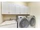 Well-equipped laundry room with overhead storage cabinets, a sink, and front loading washer and dryer at 116 Pescador Pl, Nokomis, FL 34275