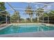 Refreshing in-ground pool enclosed by a screened lanai, surrounded by lush greenery at 1248 Jefferson Dr, Englewood, FL 34224