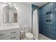 Stylish bathroom with blue tiled shower, white vanity, and gold fixtures for an elegant look at 125 12Th E Ave, Palmetto, FL 34221