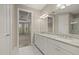 Main bathroom featuring double sinks, white cabinetry, and doorway to bedroom at 12659 Sorrento Way, Bradenton, FL 34211