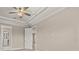 Neutral main bedroom with tray ceiling, ceiling fan, and adjoining areas at 12659 Sorrento Way, Bradenton, FL 34211
