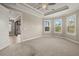 Bright main bedroom featuring a tray ceiling, neutral carpet, and large windows at 12659 Sorrento Way, Bradenton, FL 34211