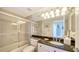 Bathroom with a granite countertop, sliding glass shower door, and modern lighting at 1800 Benjamin Franklin Dr # B308, Sarasota, FL 34236