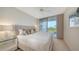 Bright bedroom features a ceiling fan and a sliding glass door to balcony overlooking trees at 1800 Benjamin Franklin Dr # B308, Sarasota, FL 34236