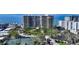 High-rise beachfront building showcasing a scenic view of the ocean, surrounded by lush landscaping and a tennis court at 1800 Benjamin Franklin Dr # B308, Sarasota, FL 34236