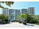 Large building with balconies in a tropical setting surrounded by palm trees at 1800 Benjamin Franklin Dr # B308, Sarasota, FL 34236