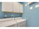 A laundry room with a blue wall and a front loading washer and dryer at 1800 Benjamin Franklin Dr # B308, Sarasota, FL 34236