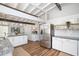 Open-concept kitchen with stainless steel refrigerator, white cabinets, granite counters, and wood-look flooring for a cohesive look at 2213 Wason Rd, Sarasota, FL 34231