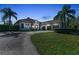 Well-designed single-Gathering home with a long driveway, a well-manicured lawn, and a three-car garage at dusk at 22354 Panther Loop, Bradenton, FL 34202