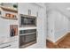 Built-in stainless steel microwave and oven with white cabinets and brick flooring in kitchen at 22354 Panther Loop, Bradenton, FL 34202