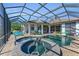 Impressive pool area with a stone hot tub, screened-in enclosure, outdoor kitchen, and lounge seating for stylish outdoor living at 22354 Panther Loop, Bradenton, FL 34202