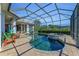 Captivating pool featuring a stone hot tub, screened-in enclosure, lush landscaping, and brick paver deck for relaxation at 22354 Panther Loop, Bradenton, FL 34202
