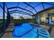 Stunning evening shot of the screened-in pool featuring LED lighting, a stone hot tub, and brick paver deck for ambiance at 22354 Panther Loop, Bradenton, FL 34202