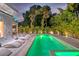 Backyard pool illuminated at twilight surrounded by lush landscaping and patio loungers at 2327 Hillview St, Sarasota, FL 34239