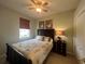 This bedroom features a ceiling fan, window, bed, nightstand with lamp and two pieces of framed art at 2334 Felicity Pl, North Port, FL 34289