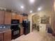 A well-lit kitchen features wooden cabinets, granite countertops, and modern black appliances at 2334 Felicity Pl, North Port, FL 34289