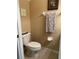 Powder room showing toilet, towel bar with grey patterned towel, artwork and tile flooring at 2334 Felicity Pl, North Port, FL 34289
