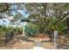Community playground with play structure, slide, and seating amidst mature trees in a fenced area at 2384 Midnight Pearl Dr, Sarasota, FL 34240