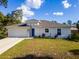 Charming single-story home featuring a two-car garage, blue door, neutral stucco, and well-maintained lawn at 3438 Alwood St, North Port, FL 34291