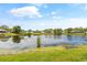 Scenic view of a tranquil pond surrounded by lush greenery, neighborhood homes, and a clear blue sky at 3611 22Nd W Ave, Bradenton, FL 34205