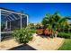 Beautiful backyard with a screened-in pool area, lush landscaping, and charming wooden bridge at 3707 5Th Ne Ave, Bradenton, FL 34208