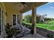 Inviting covered patio with rocking chairs and a ceiling fan with views to the spacious lawn and landscaping at 402 Walls Way, Osprey, FL 34229